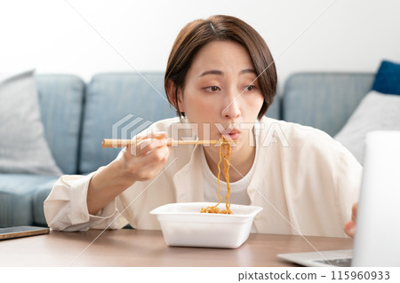 Woman eating cup fried noodles 115960933