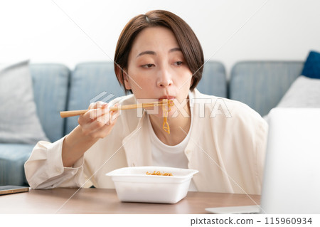 Woman eating cup fried noodles 115960934