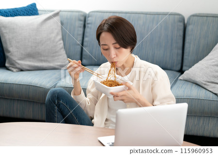 Woman eating cup fried noodles 115960953