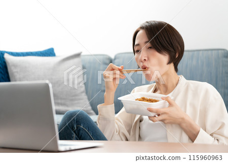 Woman eating cup fried noodles 115960963