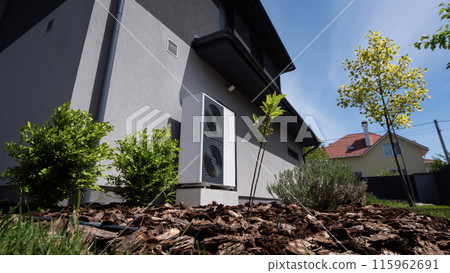 Outdoor unit of a heat pump against the wall of a modern cottage 115962691