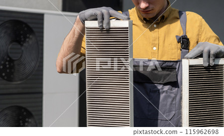 Plumber holding heavily clogged air filters from a home air conditioning system. Plumber holding heavily clogged air filters from a home air conditioning system. 115962698