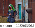 Portrait of a greenhaired girl in chekered dress with joker makeup on a rusty metal wall background. 115963568
