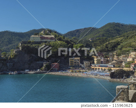 Picturesque view of Monterosso al Mare with beach, colorful houses, train rails, bell tower and Torre Bastioni with green cliffs, clear blue sky and sea. National park Cinque Terre, Liguria, Italy 115963625