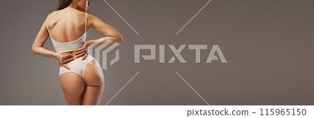 Banner. Rear view photo of young woman with healthy back poses against warm grey studio background with negative space to insert your text. Banner. Rear view photo of young woman with healthy back poses against warm grey studio background with negative space to insert your text. 115965150