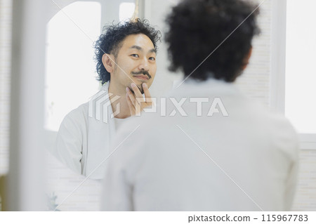 A man suffering from skin problems while looking in the mirror 115967783