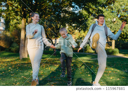 a family mom and 2 sons are having fun, running in the park and jumping. Sons, children, mom, run, play, rejoice, enjoy nature in summer. Family teamwork. Happy family team, running together in field 115967881