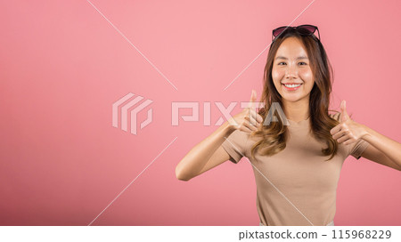 Portrait Asian beautiful young woman smiling she standing made finger thumbs up, Ok sign to agree studio shot isolated on pink background, Thai female successful like finger gesture with copy space 115968229