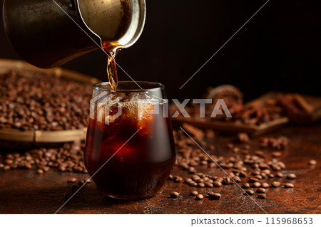 Black iced coffee with coffee beans on a brown vintage table. 115968653