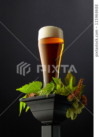 Beer with green hops and wheat ears on a black podium. Beer with green hops and wheat ears on a black podium. 115968688