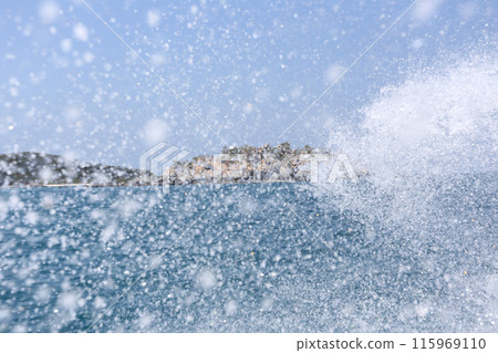 View of the sea with islands in the background and spray from the waves of a speedboat. 115969110