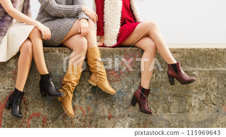 Three women presenting shoes outdoor 115969643