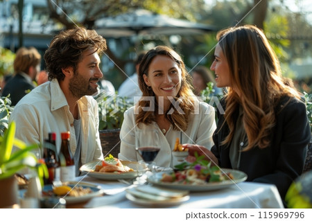 Three friends dining outdoors at a restaurant, enjoying meal and conversation under the sunshine. Three friends dining outdoors at a restaurant, enjoying meal and conversation under the sunshine. 115969796