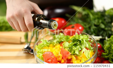 Cook holds bottle in hand and trickles olive 115970431