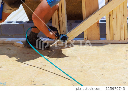 An air nail hammer is used by framing contractor to nail wooden beams An air nail hammer is used by framing contractor to nail wooden beams 115970743
