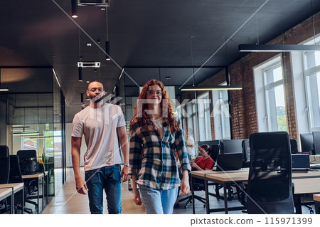 A young African American businessman and a modern businesswoman with orange hair stand side by side, arms crossed, exuding confidence and unity in a contemporary office setting, epitomizing dynamic 115971399