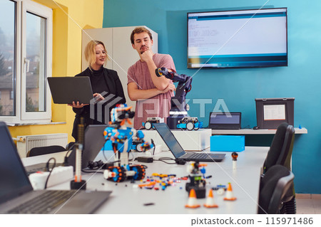 A group of colleagues working together in a robotics laboratory, focusing on the intricate fields of robotics and 3D printing. Showcase their dedication to innovation, as they engage in research 115971486
