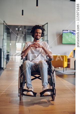 A businessman in a wheelchair occupies a hallway within a modern startup coworking center, embodying inclusivity and determination in the business environment 115971688