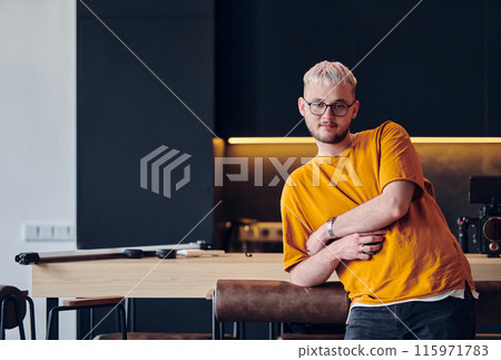 A man takes a brief rest from work in a modern startup coworking center, using the moment to recharge and relax with technology by his side. 115971783