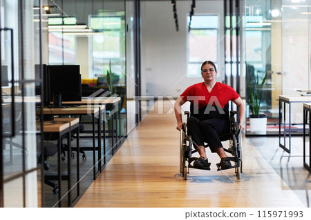A modern young businesswoman in a wheelchair is surrounded by an inclusive workspace with glass-walled offices, embodying determination and innovation in the business world 115971993