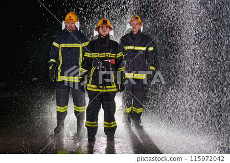 A group of professional firefighters marching through the rainy night on a rescue mission, their determined strides and fearless expressions reflecting their unwavering bravery and unwavering 115972042