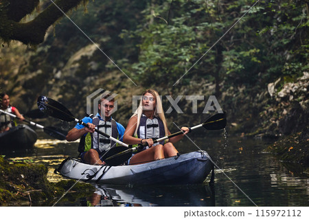 A group of friends enjoying having fun and kayaking while exploring the calm river, surrounding forest and large natural river canyons 115972112