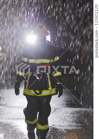 A determined female firefighter in a professional uniform striding through the dangerous, rainy night on a daring rescue mission, showcasing her unwavering bravery and commitment to saving lives. 115972120