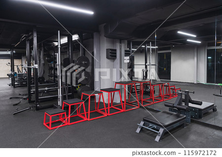 An empty modern gymnasium with a variety of equipment, offering a spacious, functional, and well-equipped training facility for workouts, fitness, and strength training 115972172