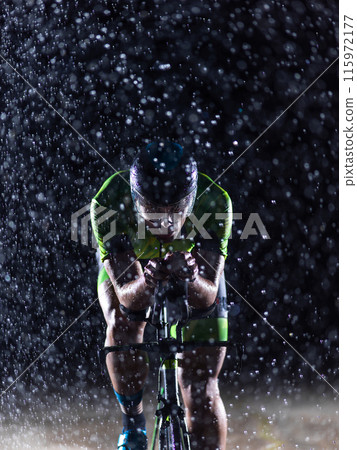 A triathlete braving the rain as he cycles through the night, preparing himself for the upcoming marathon 115972177