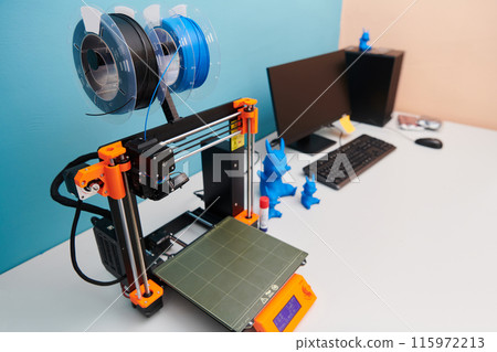 Modern 3d printer for creating 3d models and materials on the table in the laboratories next to the computer Modern 3d printer for creating 3d models and materials on the table in the laboratories next to the computer 115972213