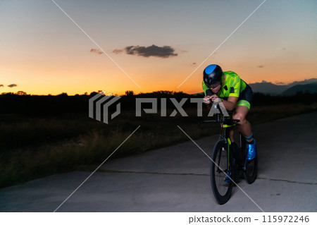 A triathlete rides his bike in the darkness of night, pushing himself to prepare for a marathon. The contrast between the darkness and the light of his bike creates a sense of drama and highlights the 115972246