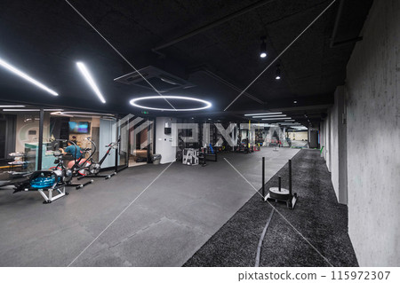 An empty modern gymnasium with a variety of equipment, offering a spacious, functional, and well-equipped training facility for workouts, fitness, and strength training 115972307