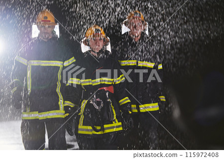 A group of professional firefighters marching through the rainy night on a rescue mission, their determined strides and fearless expressions reflecting their unwavering bravery and unwavering A group of professional firefighters marching through the rainy night on a rescue mission, their determined strides and fearless expressions reflecting their unwavering bravery and unwavering 115972408