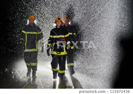 A group of professional firefighters marching through the rainy night on a rescue mission, their determined strides and fearless expressions reflecting their unwavering bravery and unwavering 115972436