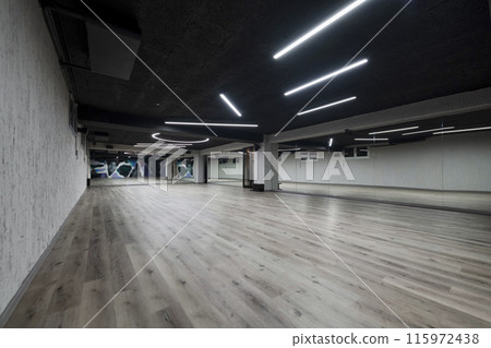 An empty dance hall with a glass wall adorned with decorative graffiti, offering a fusion of contemporary, urban artistic ambiance and impressive aesthetics. 115972438