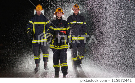 A group of professional firefighters marching through the rainy night on a rescue mission, their determined strides and fearless expressions reflecting their unwavering bravery and unwavering 115972441