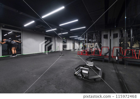 An empty modern gymnasium with a variety of equipment, offering a spacious, functional, and well-equipped training facility for workouts, fitness, and strength training 115972468