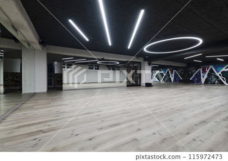 An empty dance hall with a glass wall adorned with decorative graffiti, offering a fusion of contemporary, urban artistic ambiance and impressive aesthetics. An empty dance hall with a glass wall adorned with decorative graffiti, offering a fusion of contemporary, urban artistic ambiance and impressive aesthetics. 115972473