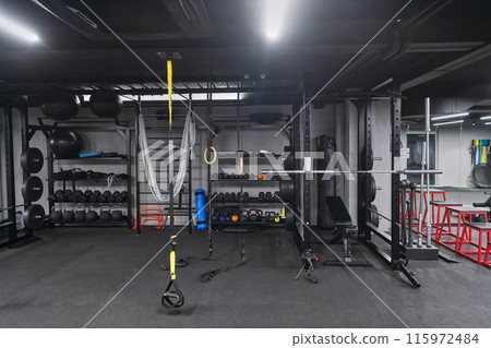 An empty modern gymnasium with a variety of equipment, offering a spacious, functional, and well-equipped training facility for workouts, fitness, and strength training 115972484