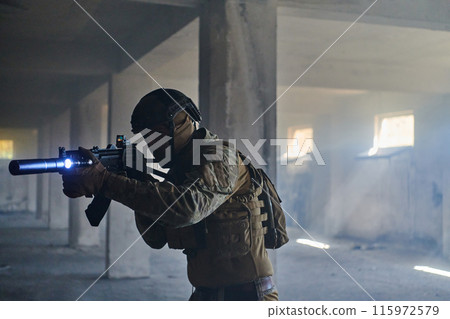 A professional soldier in an abandoned building shows courage and determination in a war campaign 115972579