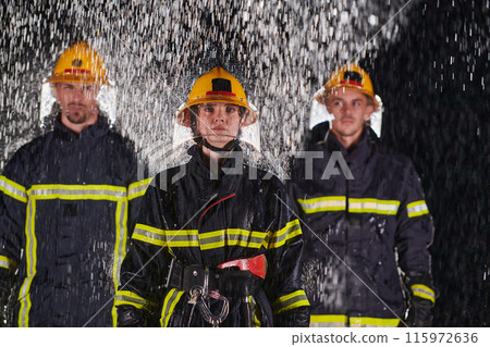 A group of professional firefighters marching through the rainy night on a rescue mission, their determined strides and fearless expressions reflecting their unwavering bravery and unwavering 115972636