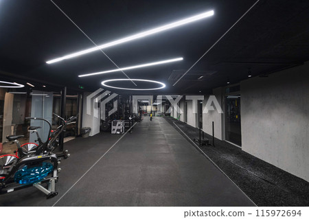 An empty modern gymnasium with a variety of equipment, offering a spacious, functional, and well-equipped training facility for workouts, fitness, and strength training 115972694