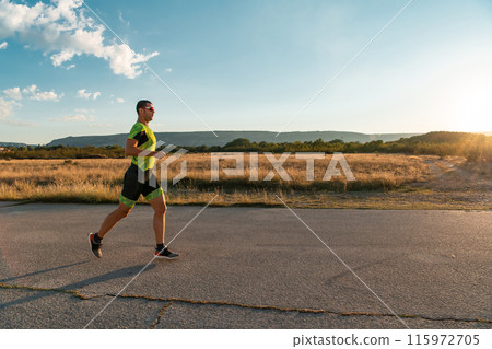 Triathlete in professional gear running early in the morning, preparing for a marathon, dedication to sport and readiness to take on the challenges of a marathon.  115972705