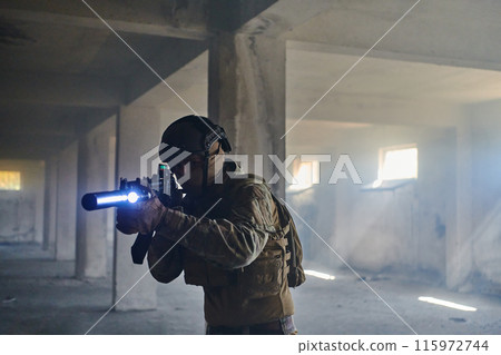 A professional soldier in an abandoned building shows courage and determination in a war campaign A professional soldier in an abandoned building shows courage and determination in a war campaign 115972744