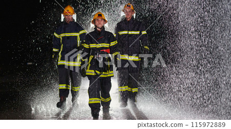 A group of professional firefighters marching through the rainy night on a rescue mission, their determined strides and fearless expressions reflecting their unwavering bravery and unwavering 115972889