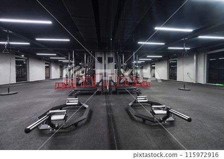An empty modern gymnasium with a variety of equipment, offering a spacious, functional, and well-equipped training facility for workouts, fitness, and strength training 115972916