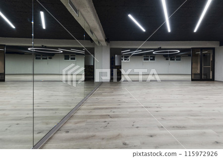 An empty dance hall with a glass wall adorned with decorative graffiti, offering a fusion of contemporary, urban artistic ambiance and impressive aesthetics. An empty dance hall with a glass wall adorned with decorative graffiti, offering a fusion of contemporary, urban artistic ambiance and impressive aesthetics. 115972926