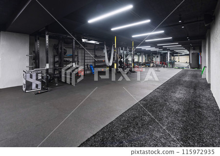 An empty modern gymnasium with a variety of equipment, offering a spacious, functional, and well-equipped training facility for workouts, fitness, and strength training 115972935