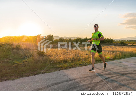 Triathlete in professional gear running early in the morning, preparing for a marathon, dedication to sport and readiness to take on the challenges of a marathon. Triathlete in professional gear running early in the morning, preparing for a marathon, dedication to sport and readiness to take on the challenges of a marathon. 115972954