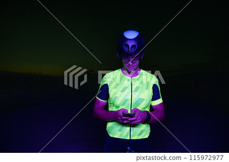 A triathlete using a smartphone while taking a break from a hard night's cycling training A triathlete using a smartphone while taking a break from a hard night's cycling training 115972977